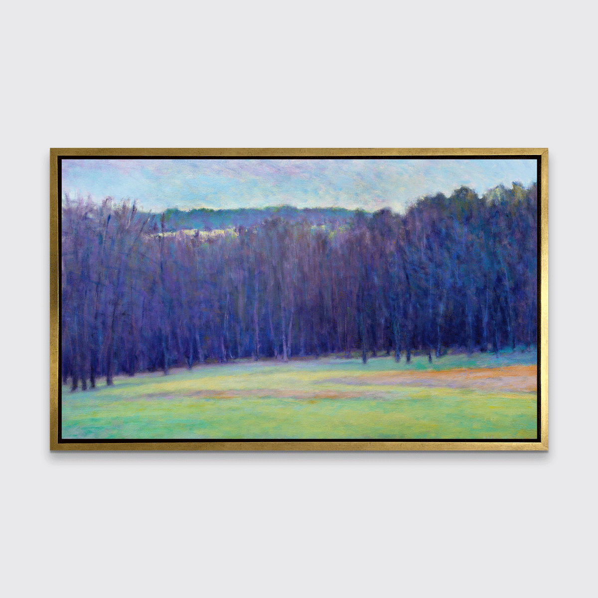 A blue, purple, light green and light orange impressionistic landscape print in a gold floater frame hangs on a white wall.