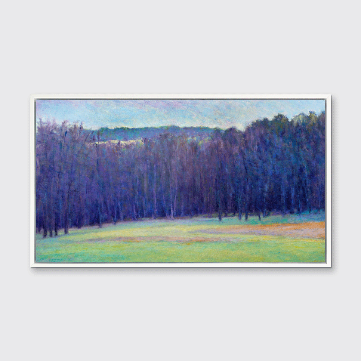 A blue, purple, light green and light orange impressionistic landscape print in a white floater frame hangs on a white wall.