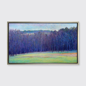 A blue, purple, light green and light orange impressionistic landscape print in a silver floater frame hangs on a white wall.