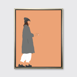 Art print of an illustrated woman wearing grey hat and coat, white pants, and grey sneakers, holding a cigarette with orange background, framed in a silver floater frame on a grey wall.
