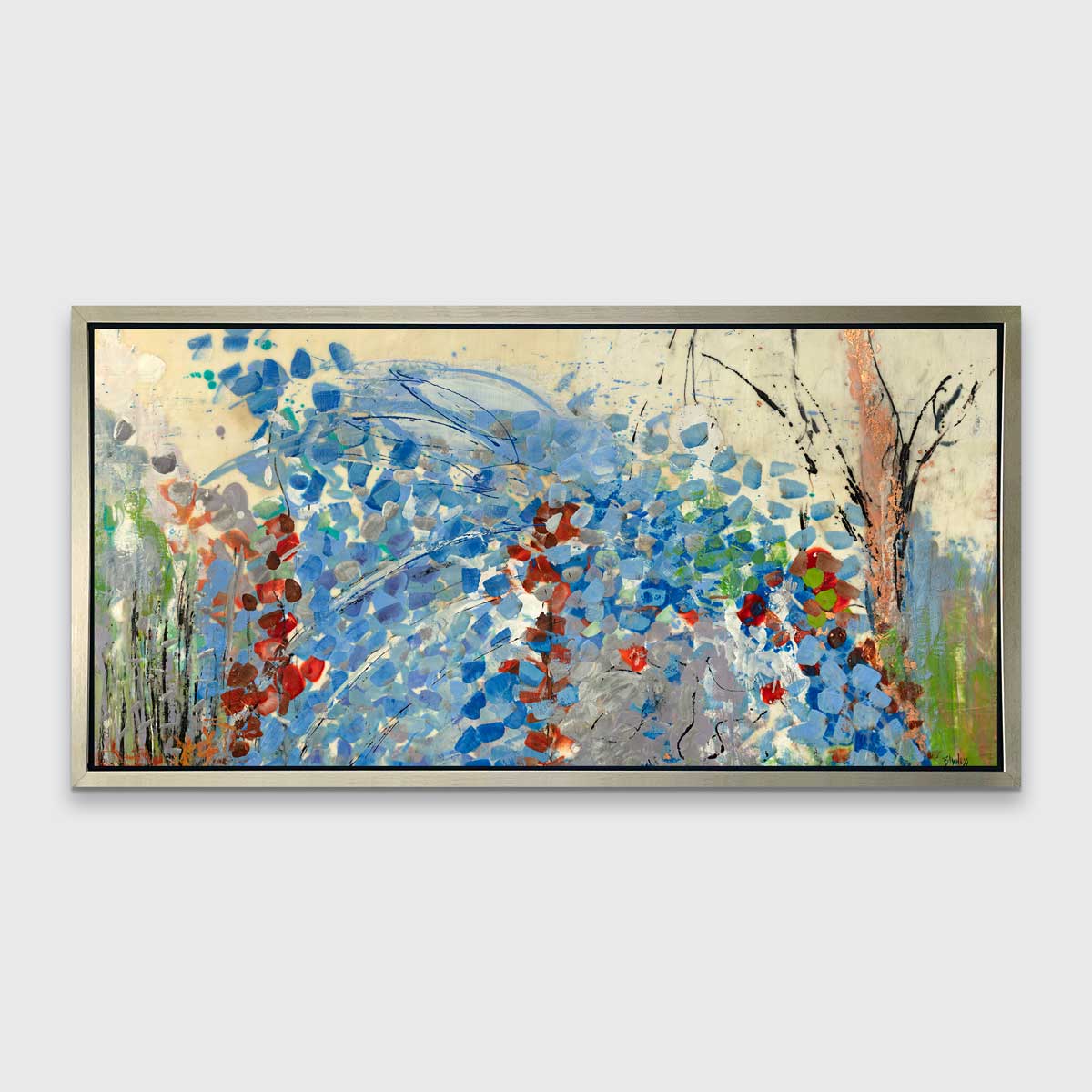 A blue, beige, green and black abstract print in a silver floater frame hangs on a white wall.