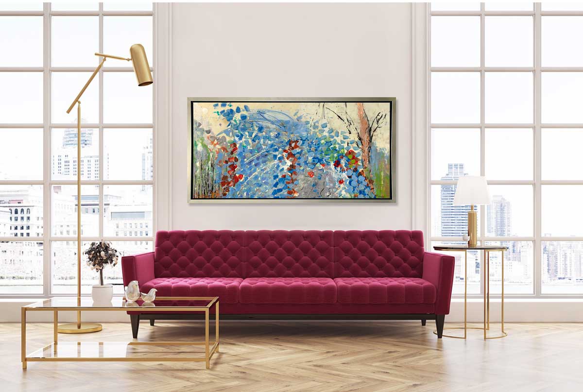 A blue, beige, green and black abstract print in a silver floater frame hangs on a white wall in between two large windows and above a raspberry tufted sofa, a gold framed coffee table with decorative accents and a tall gold adjustable floor lamp.