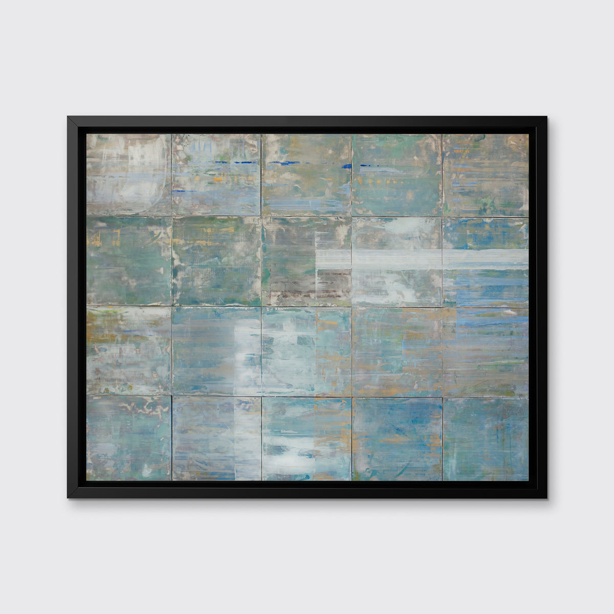 A blue and green abstract geometric print in a black floater frame hangs on a white wall.