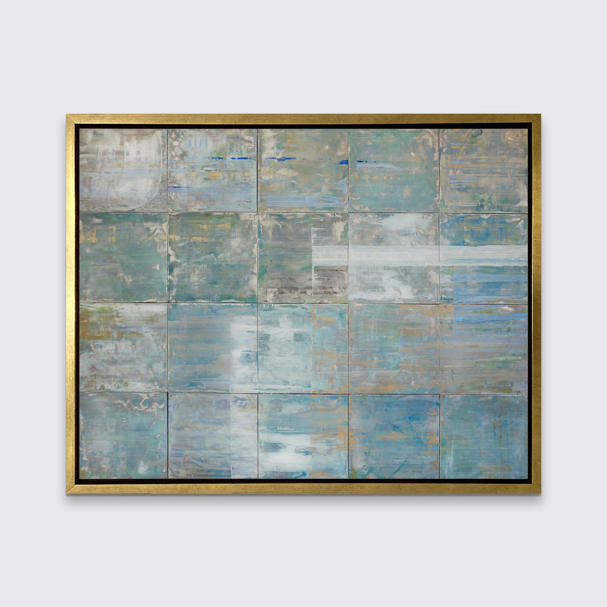 A blue and green abstract geometric print in a gold floater frame hangs on a white wall.
