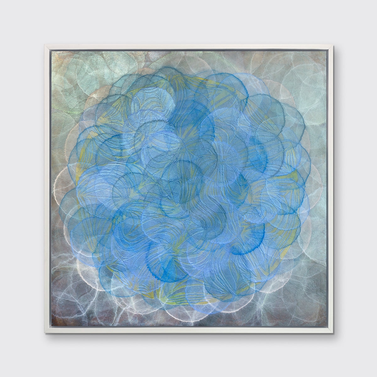 A blue, teal and light blue overlapping circle print in a white floater frame hangs on a white wall.