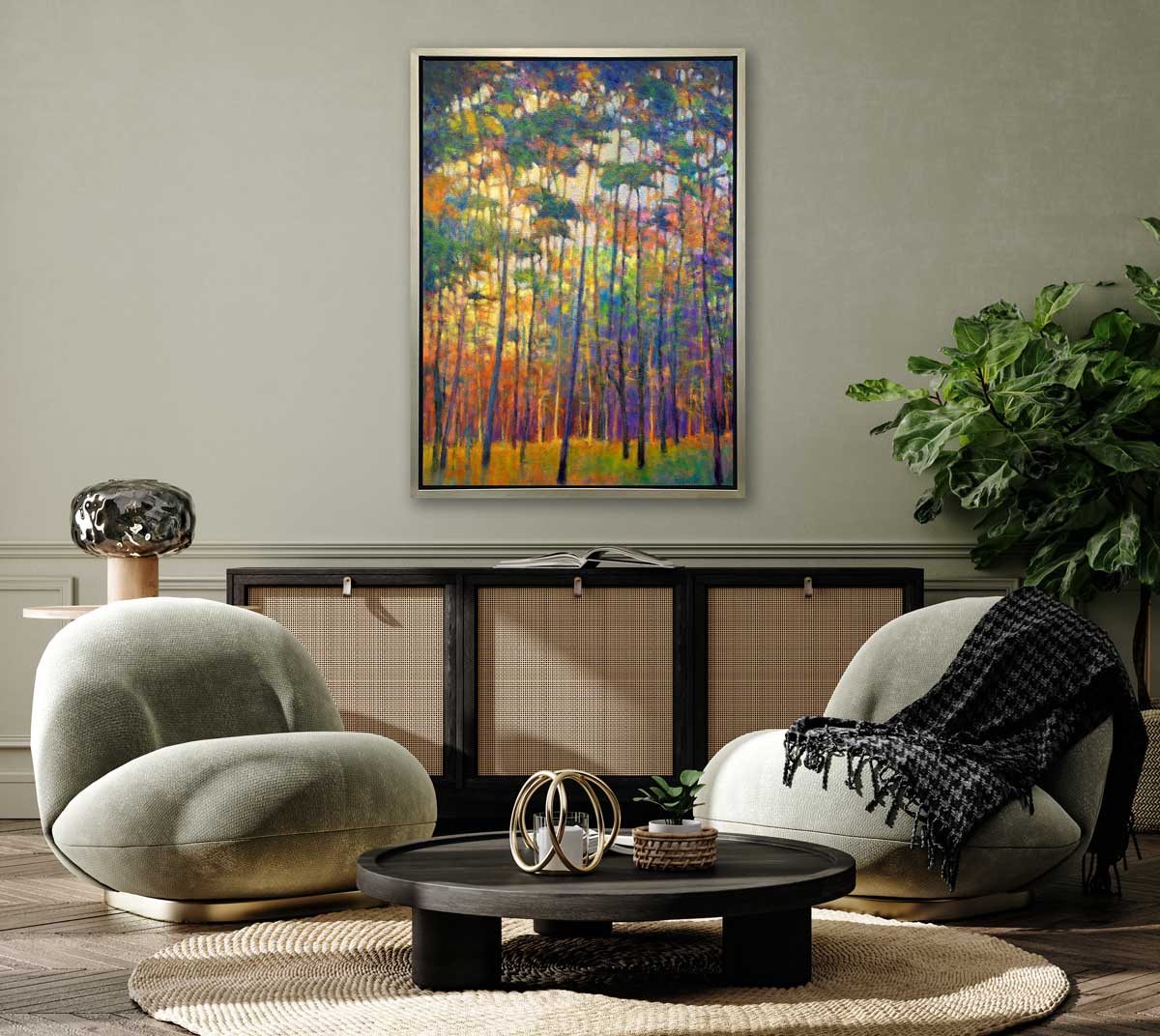 A multicolored abstract tree landscape print in a silver floater frame hangs on a light green wall above a black and rattan cabinet, two modern low light green chairs and a round black coffee table.