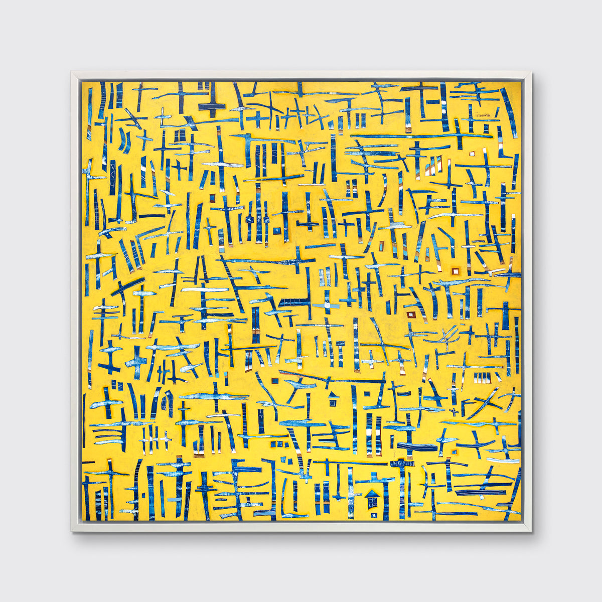 A yellow, blue and white abstract print in a white floater frame hangs on a white wall.