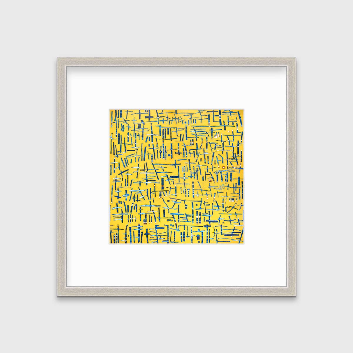 A yellow, blue and white abstract print in a silver frame with a mat hangs on a white wall.