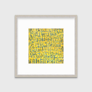 A yellow, blue and white abstract print in a silver frame with a mat hangs on a white wall.
