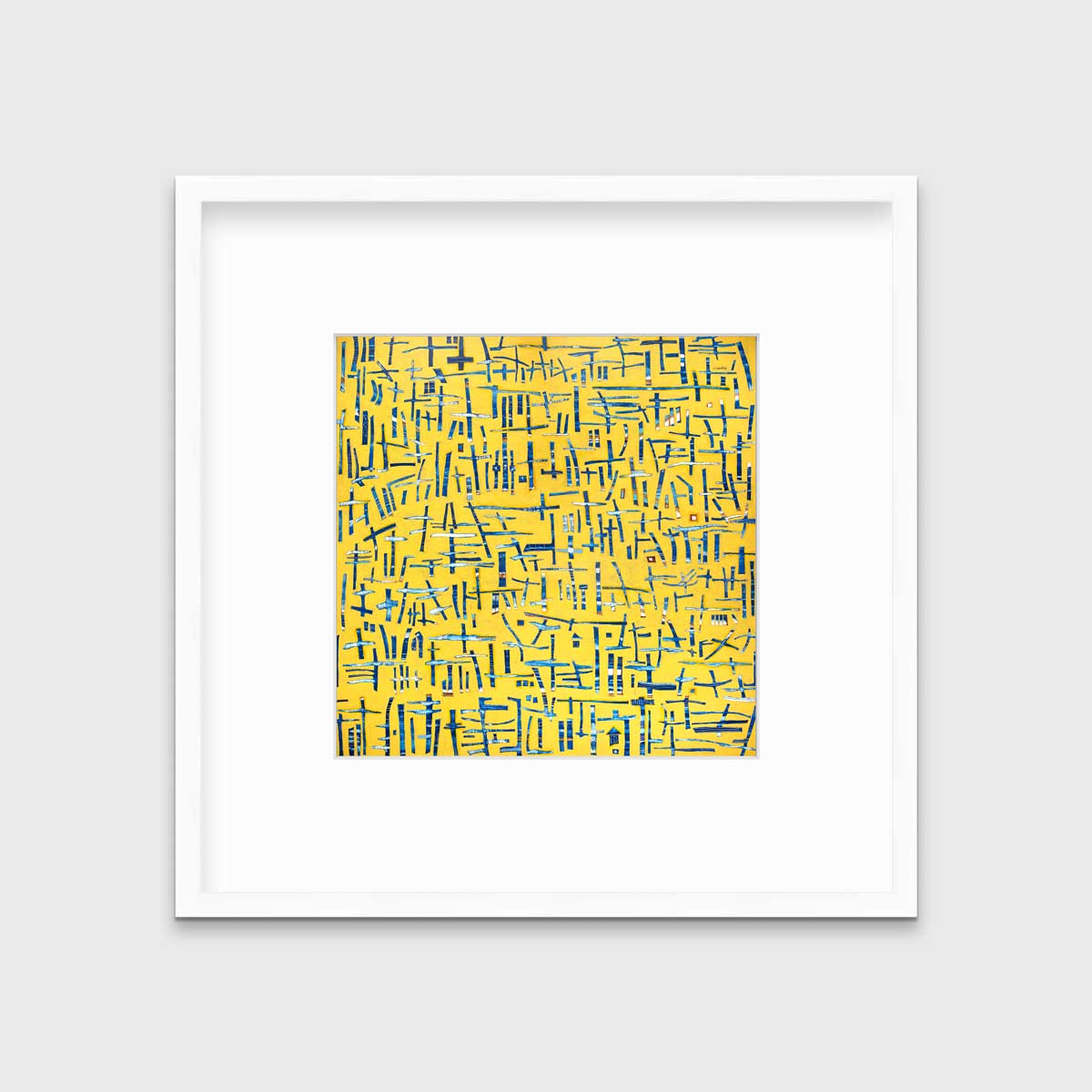 A yellow, blue and white abstract print in a white frame with a mat hangs on a white wall.