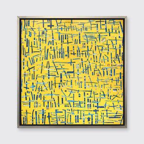 A yellow, blue and white abstract print in a silver floater frame hangs on a white wall.