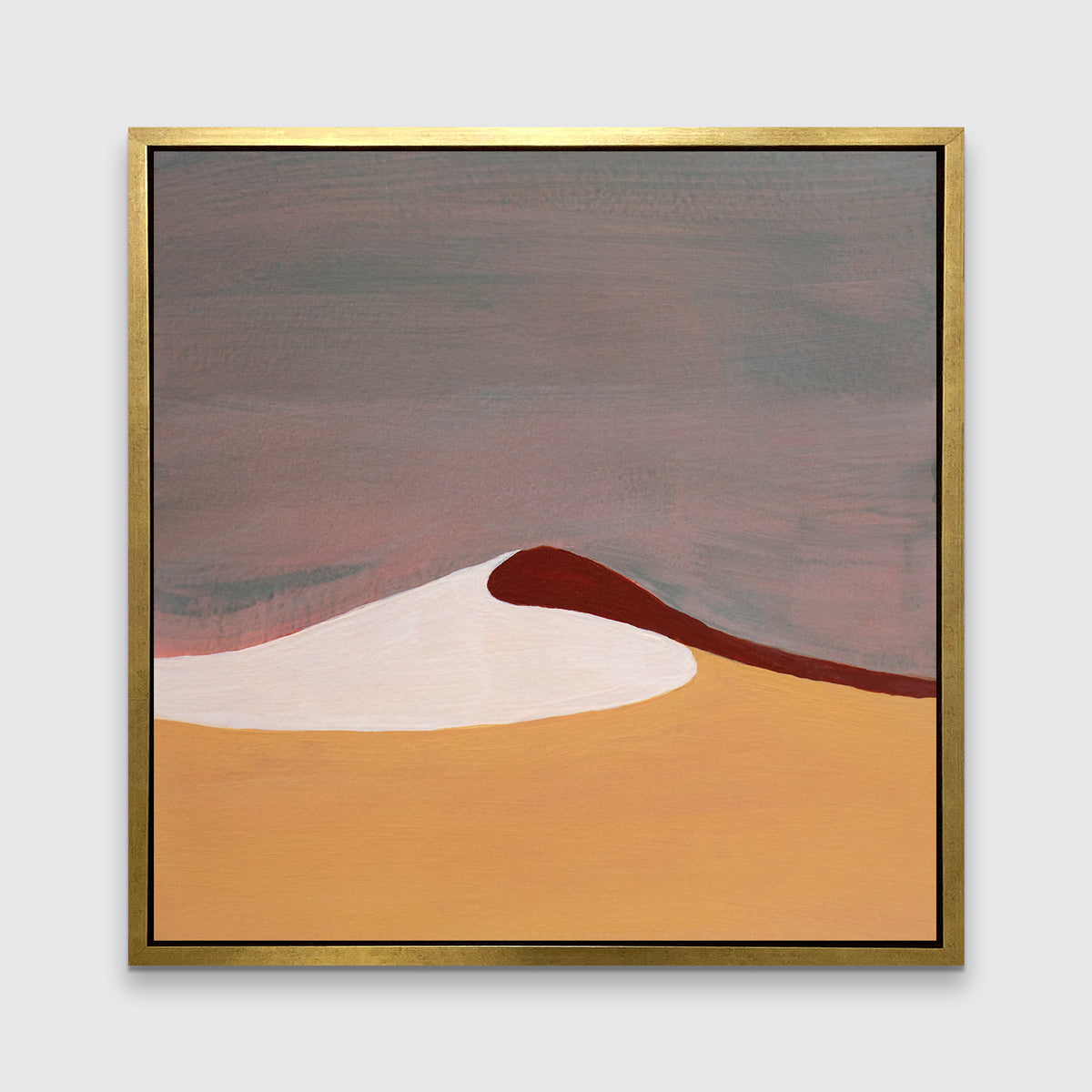 A mauve, burnt yellow, red and white abstract landscape print in a gold floater frame hangs on a white wall.