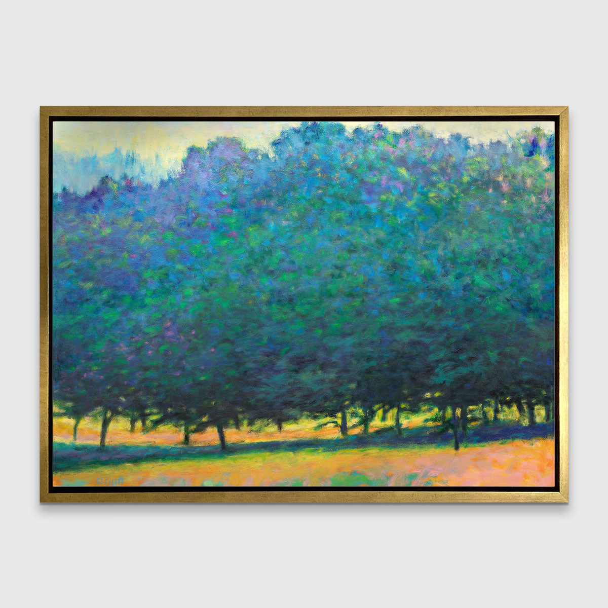 A green, orange and teal abstract tree landscape print in a gold floater frame hangs on a white wall.