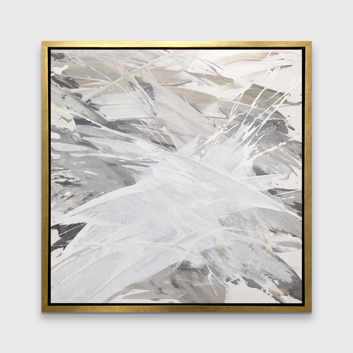 A grey, beige and white abstract print in a gold floater frame hangs on a white wall.