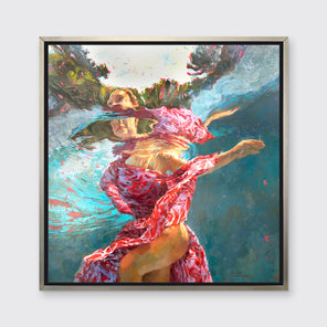 A teal, beige and red abstract distorted figurative print of a woman's body underwater with free flowing fabric in a silver floater frame hangs on a white wall.