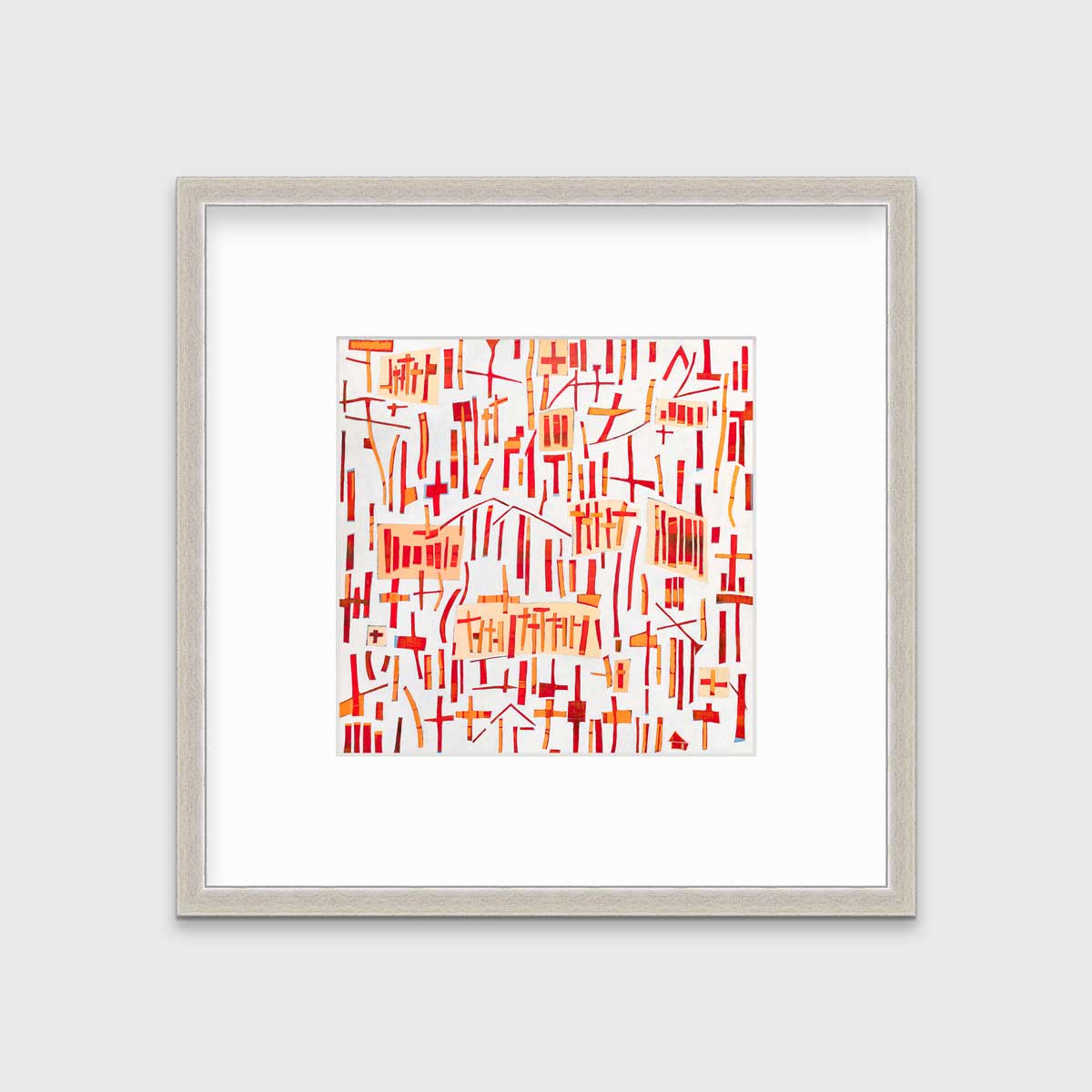 A red, orange and white abstract print in a silver frame with a mat hangs on a white wall.