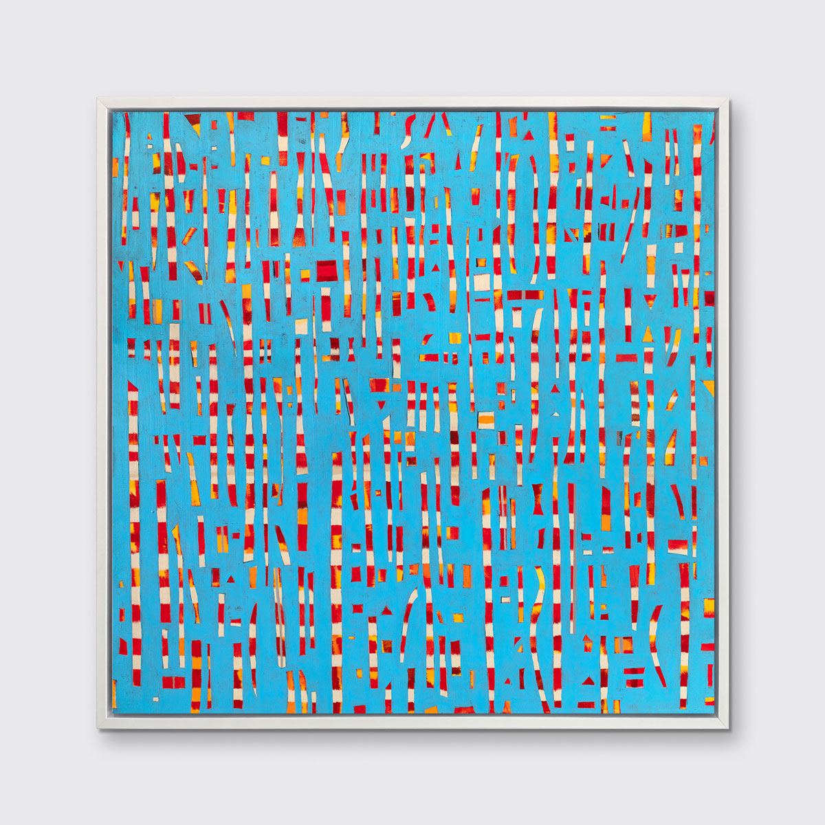 A blue, red, yellow and white abstract print in a white floater frame hangs on a white wall.