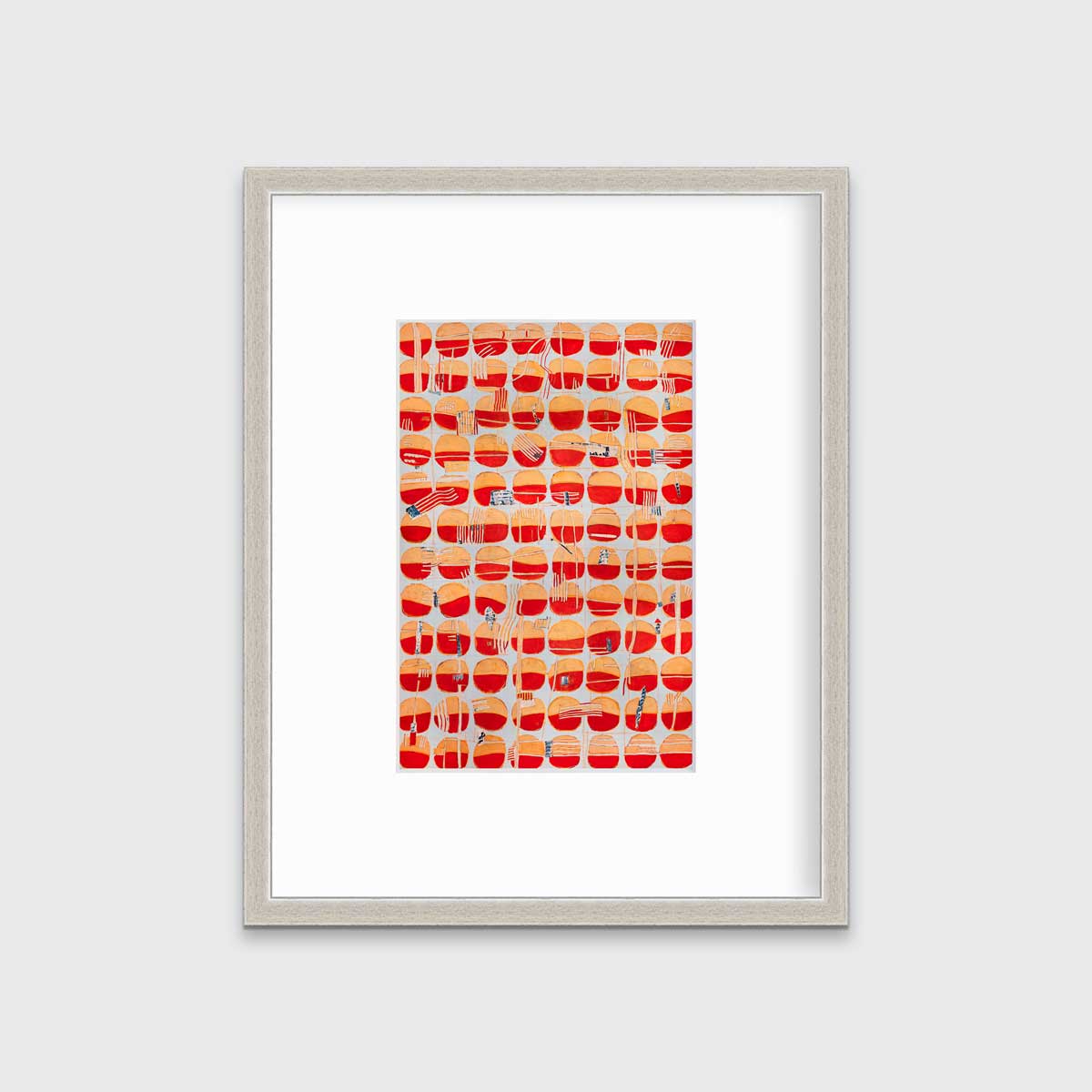 A red, orange and light blue abstract print in a silver frame with a mat hangs on a white wall.