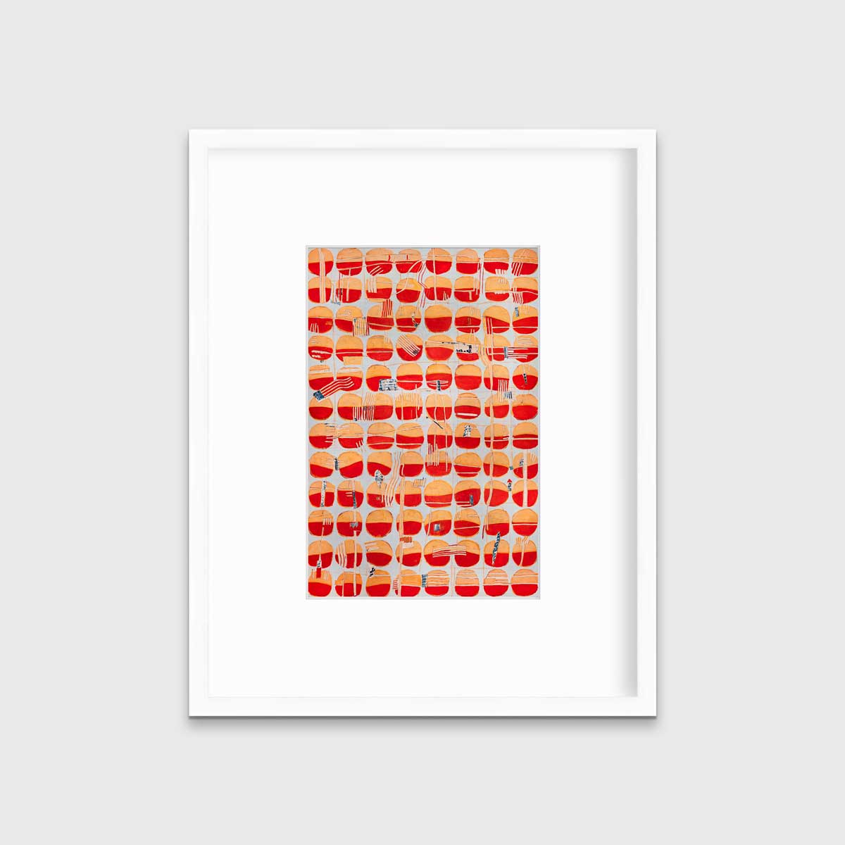 A red, orange and light blue abstract print in a white frame with a mat hangs on a white wall.