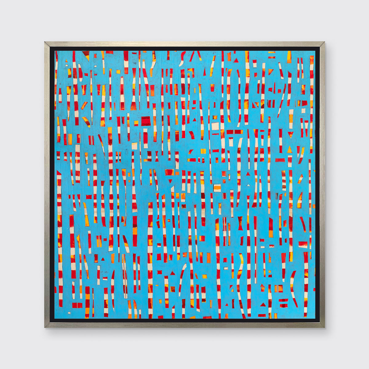 A blue, red, yellow and white abstract print in a silver floater frame hangs on a white wall.