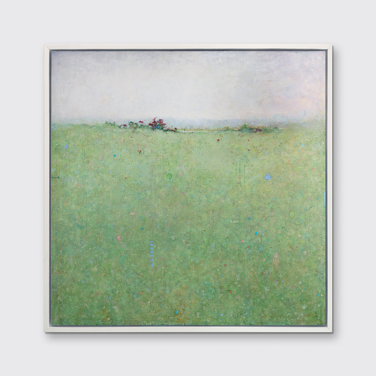 A green abstract landscape print in a white floater frame hangs on a white wall.