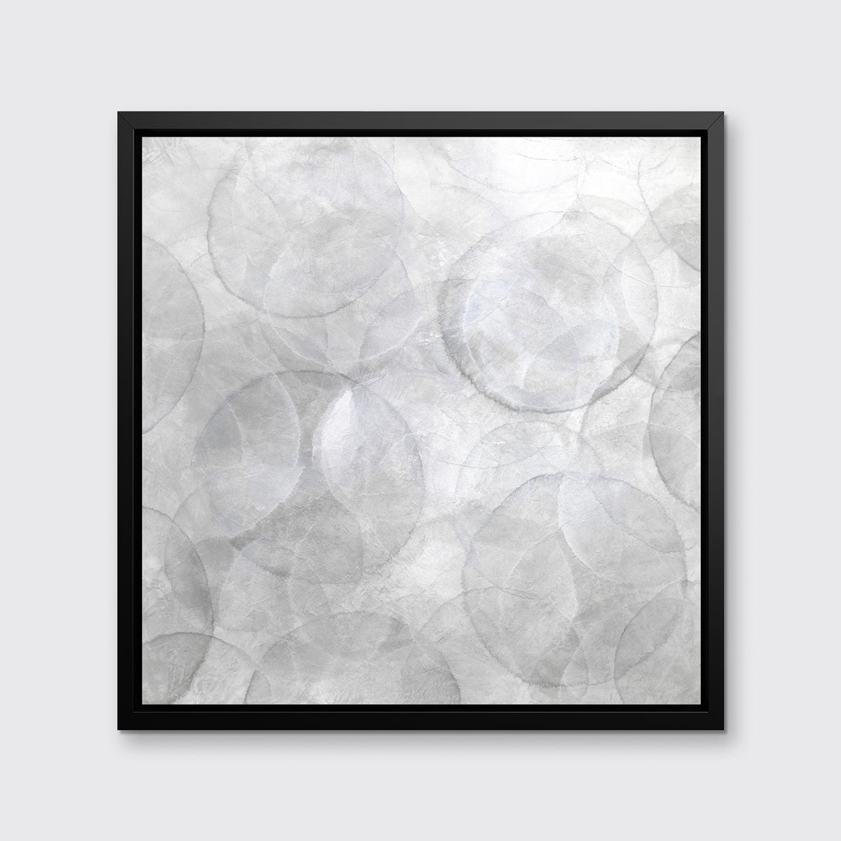 A grey and white abstract geometric print in a black floater frame hangs on a white wall.