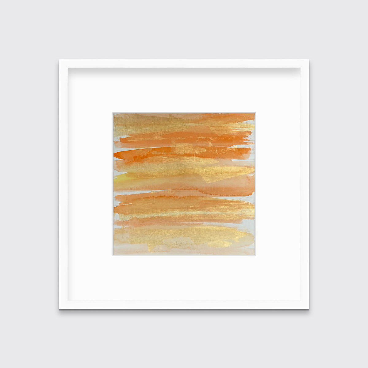 A orange, gold and white abstract print in a white frame with a mat hangs on a white wall.