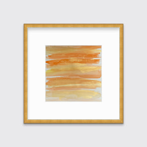 A orange, gold and white abstract print in a gold frame with a mat hangs on a white wall.