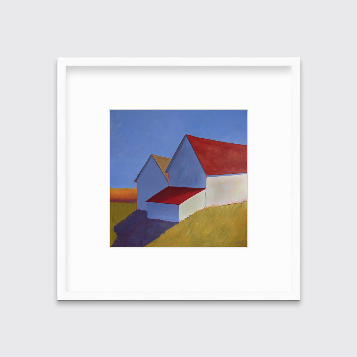 A white barn with a red roof print in a white frame with a mat hangs on a white wall.