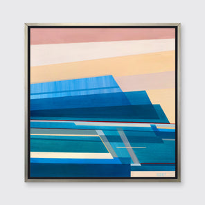 A blue, light orange and peach geometric abstract print in a silver floater frame hangs on a white wall.