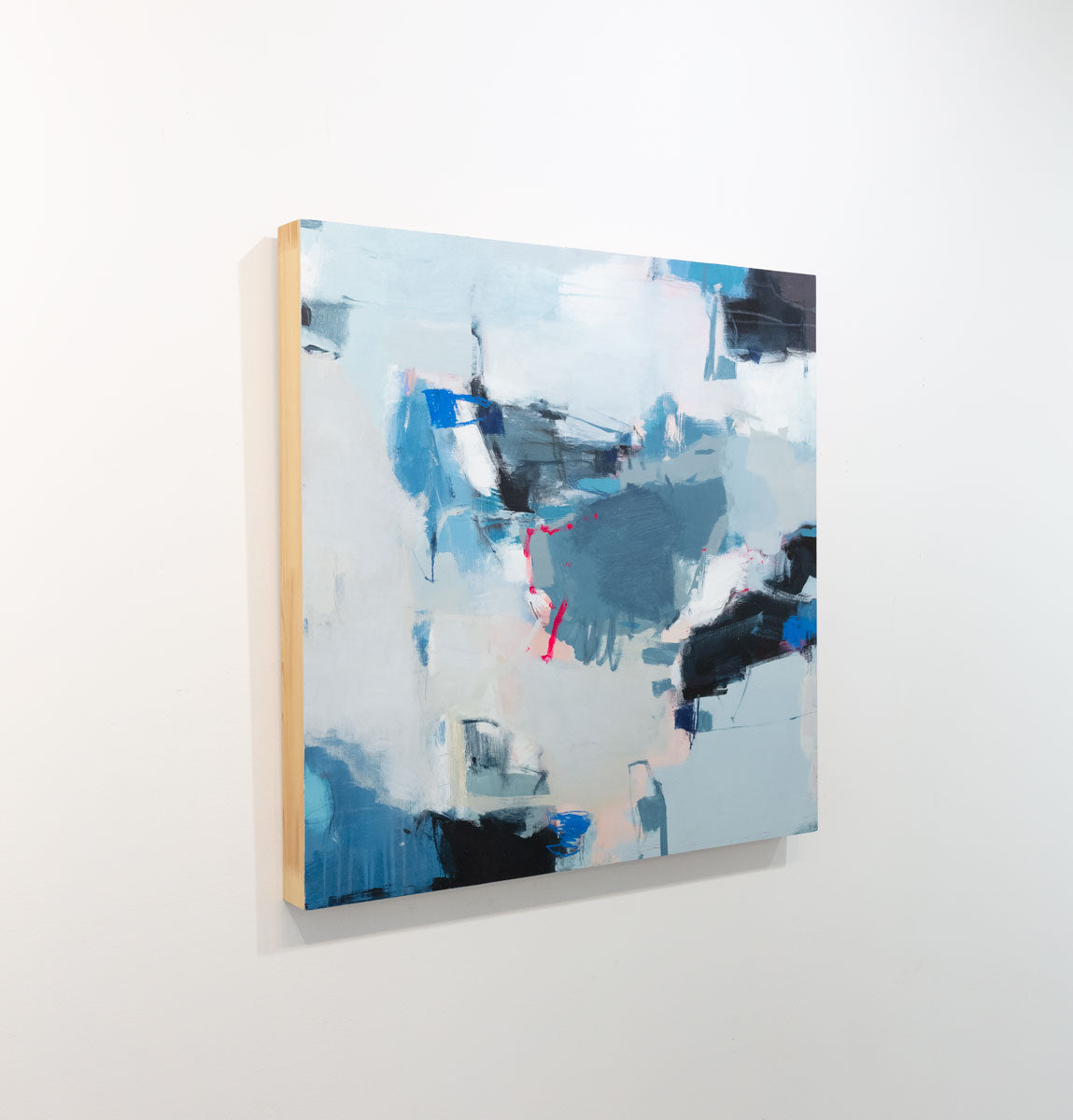 A blue, white and black abstract painting by Kelly Rossetti is seen at an angle on a gallery wall.