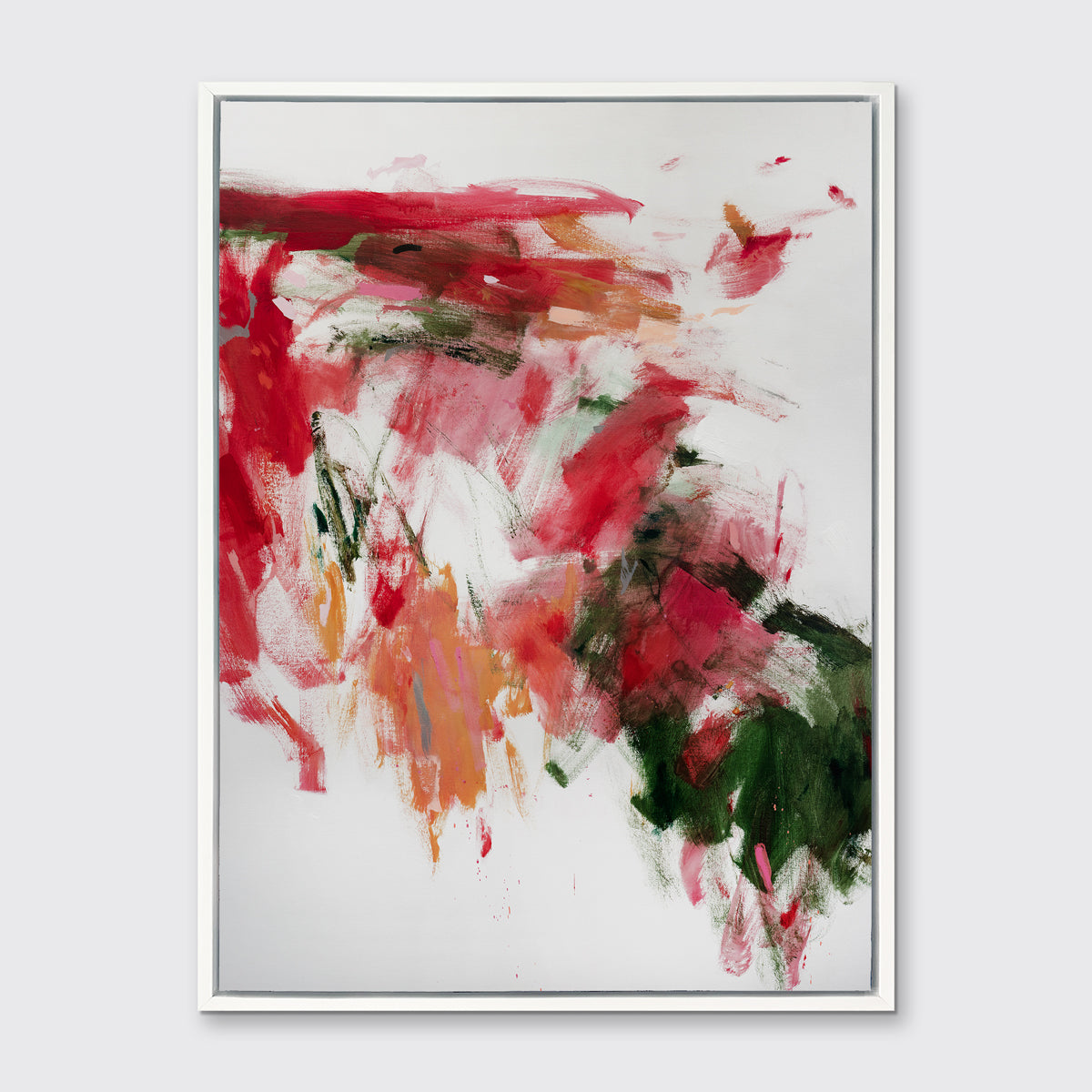 A red, green and white abstract print in a white floater frame hangs on a white wall.