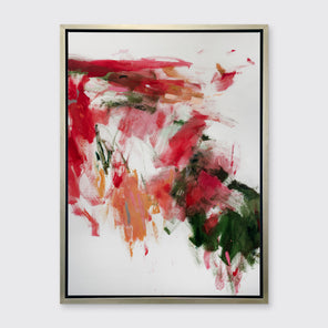 A red, green and white abstract print in a silver floater frame hangs on a white wall.
