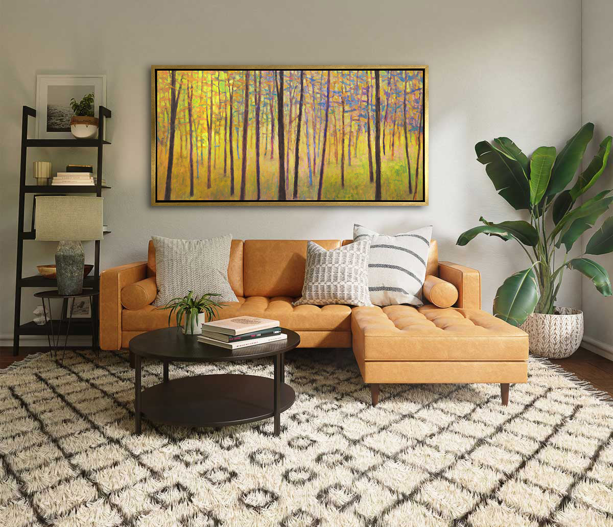 A yellow tree abstract landscape in a gold floater frame hangs on a white wall above a light orange sofa with neutral pillows, a black round coffee table, a ladder shelf and a tall potted floor plant.
