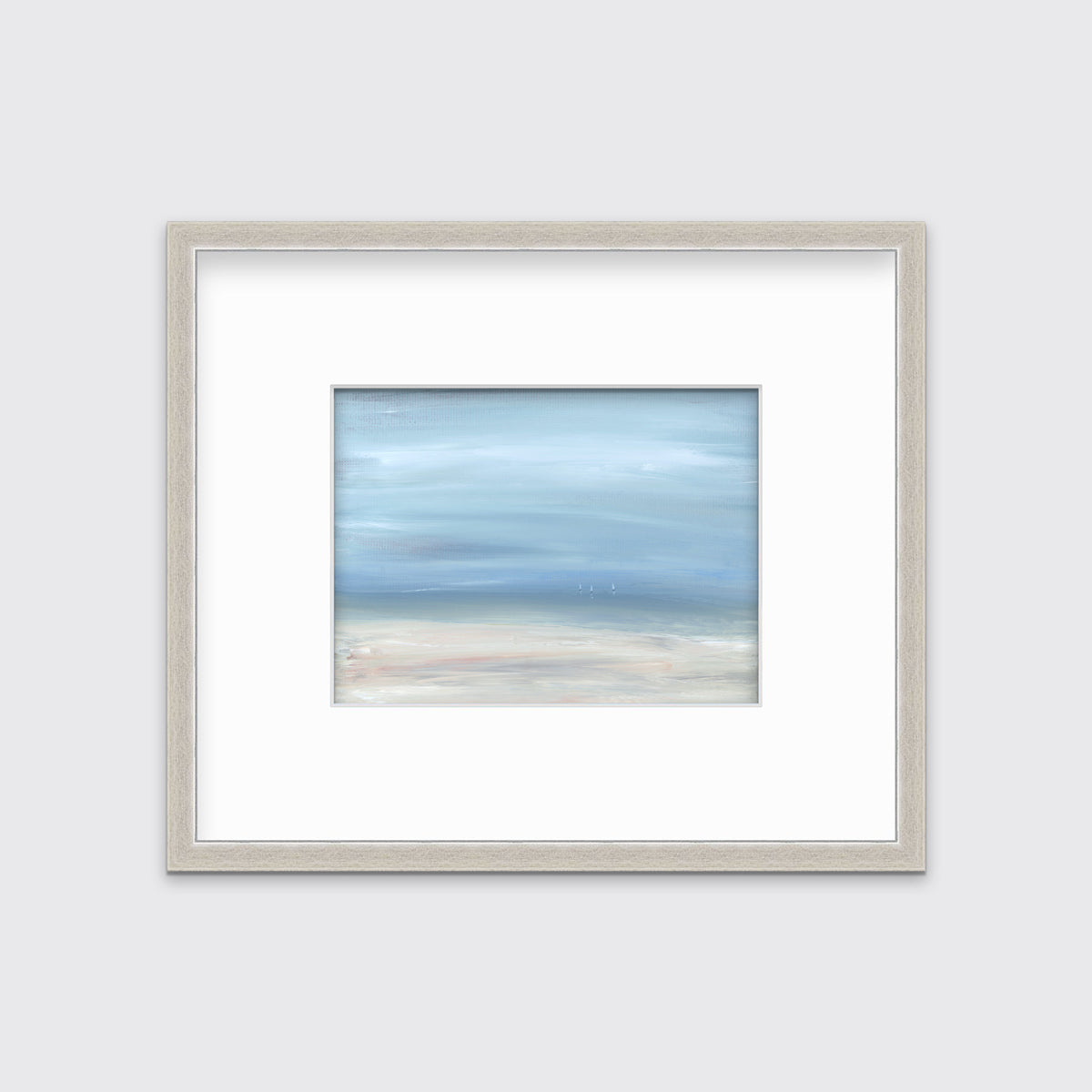 A white, blue and beige abstract seascape print in a silver frame with a mat hangs on a white wall.