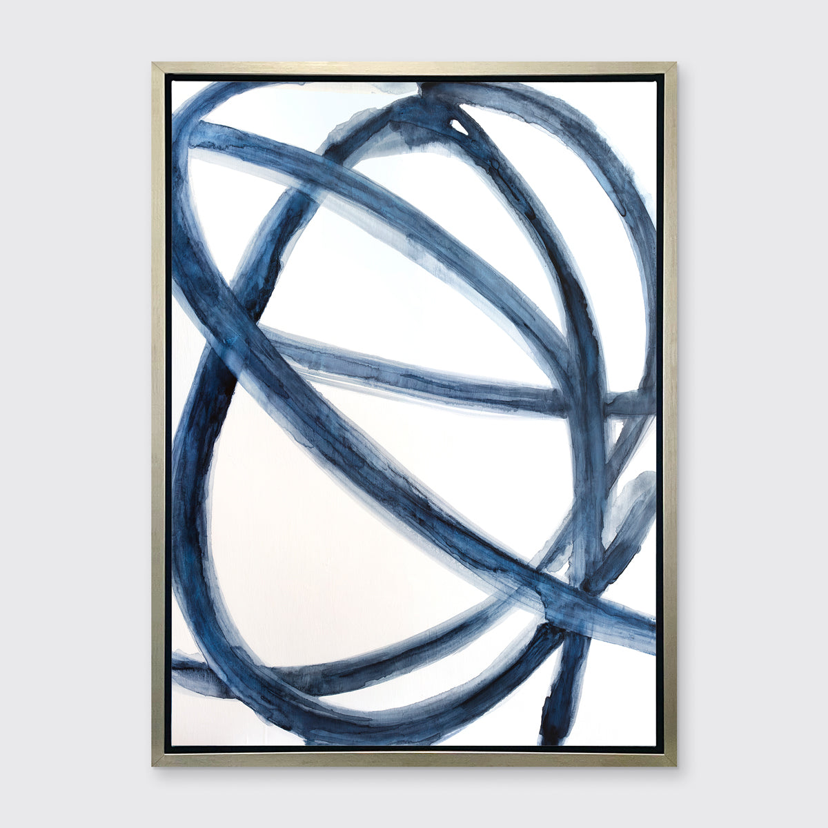 A blue and white abstract canvas print framed in a gold silver frame, hangs on a light grey wall.