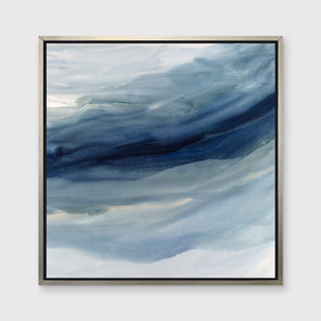 A blue, navy and white abstract print in a silver floater frame hangs on a white wall.