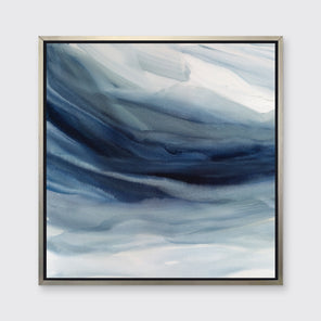 A blue, navy and white abstract print in a silver floater frame hangs on a white wall.