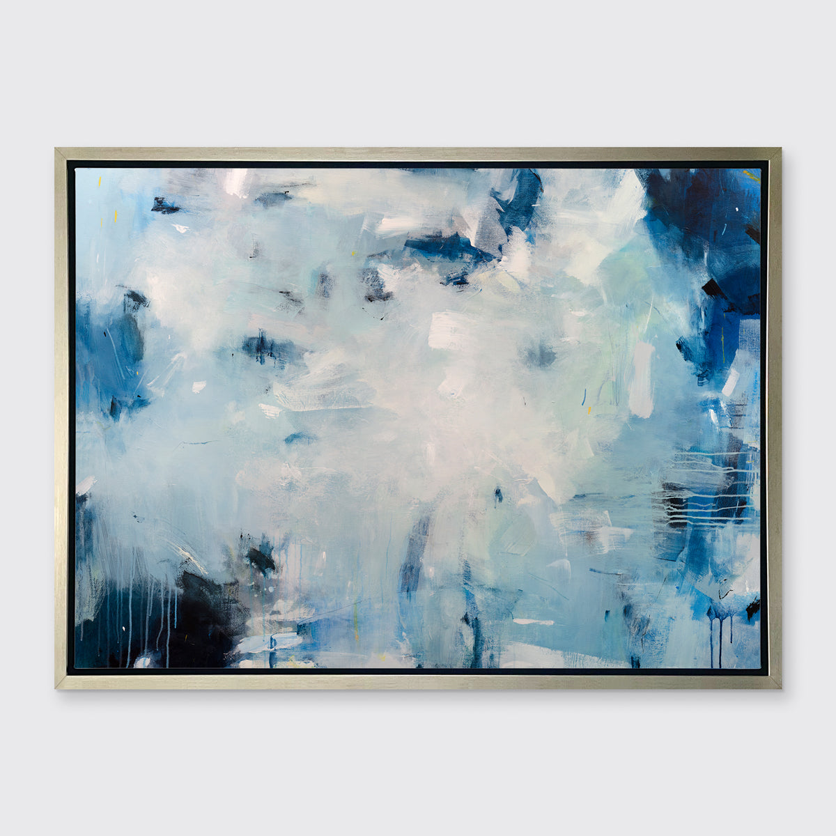 A blue, white and black abstract print in a silver floater frame hangs on a white wall.