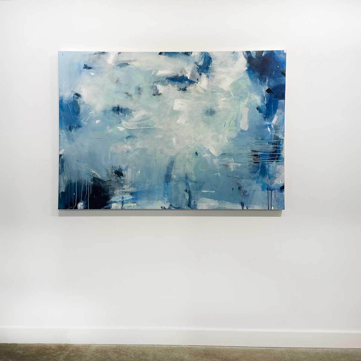 A blue and white abstract painting by Kelly Rosetti. Hangs on a white wall.