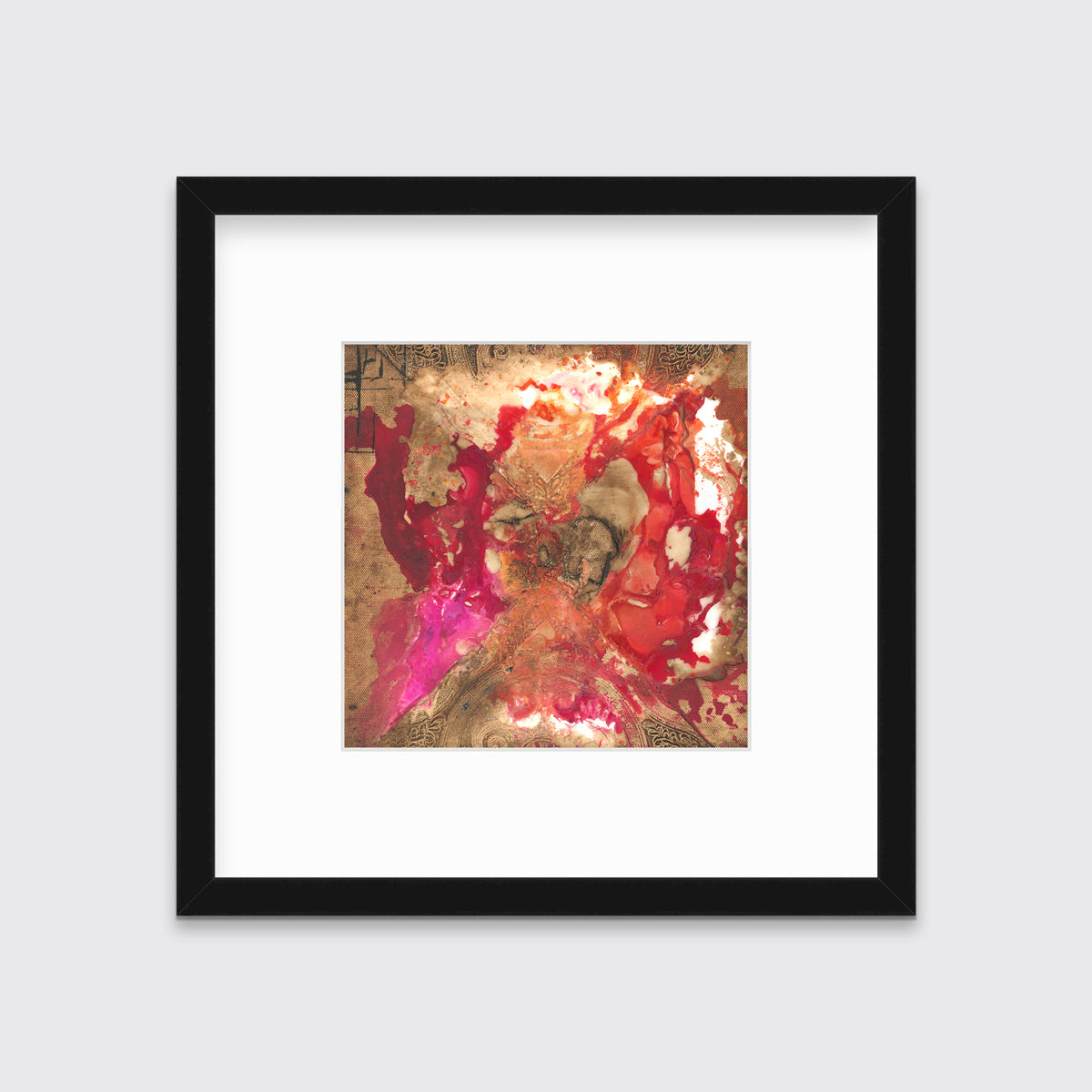 A gold, red and pink abstract print in a black frame with a mat hangs on a white wall.