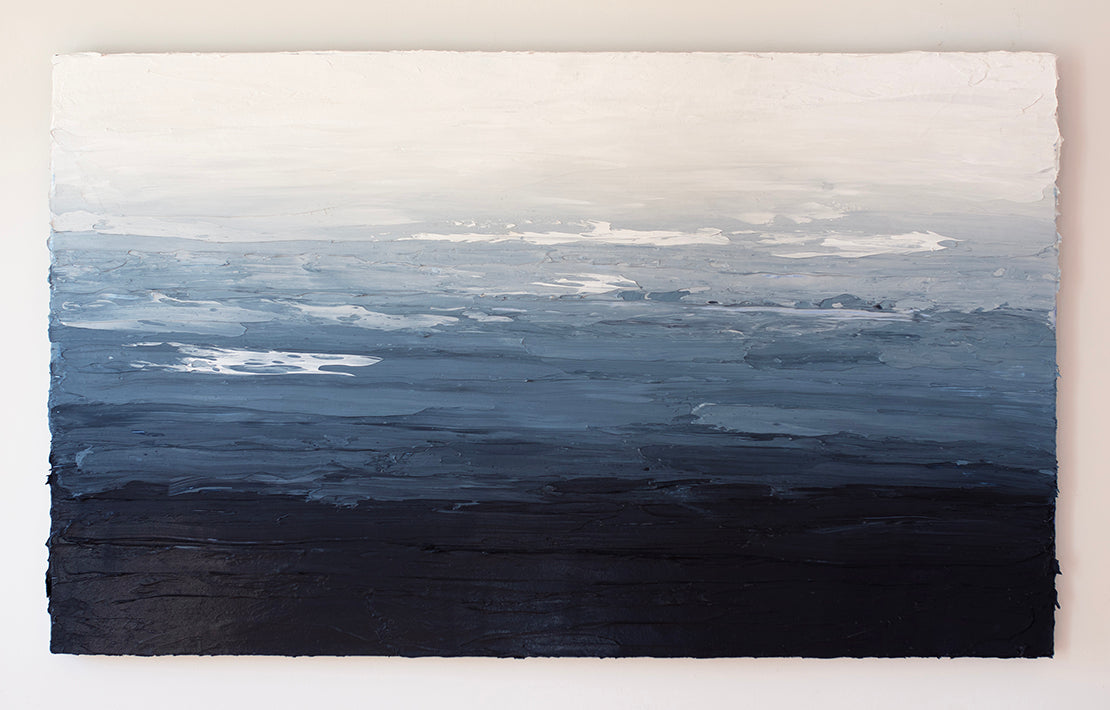 A blue, white and navy very textured abstract painting hangs on a white wall.