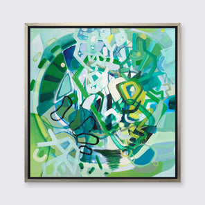 A green, teal, white and black abstract print in a silver floater frame hangs on a white wall.