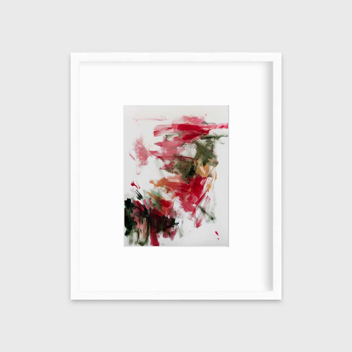 A red, green and white abstract print in a white frame with a mat hangs on a white wall.