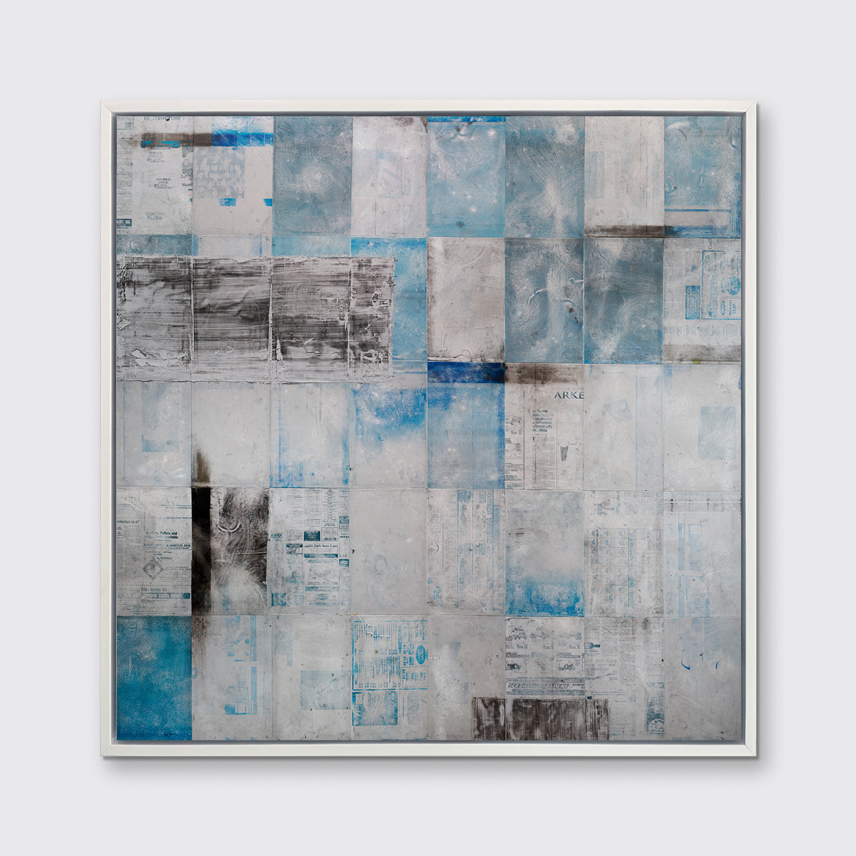 A blue, grey and black abstract print in a white floater frame hangs on a white wall.