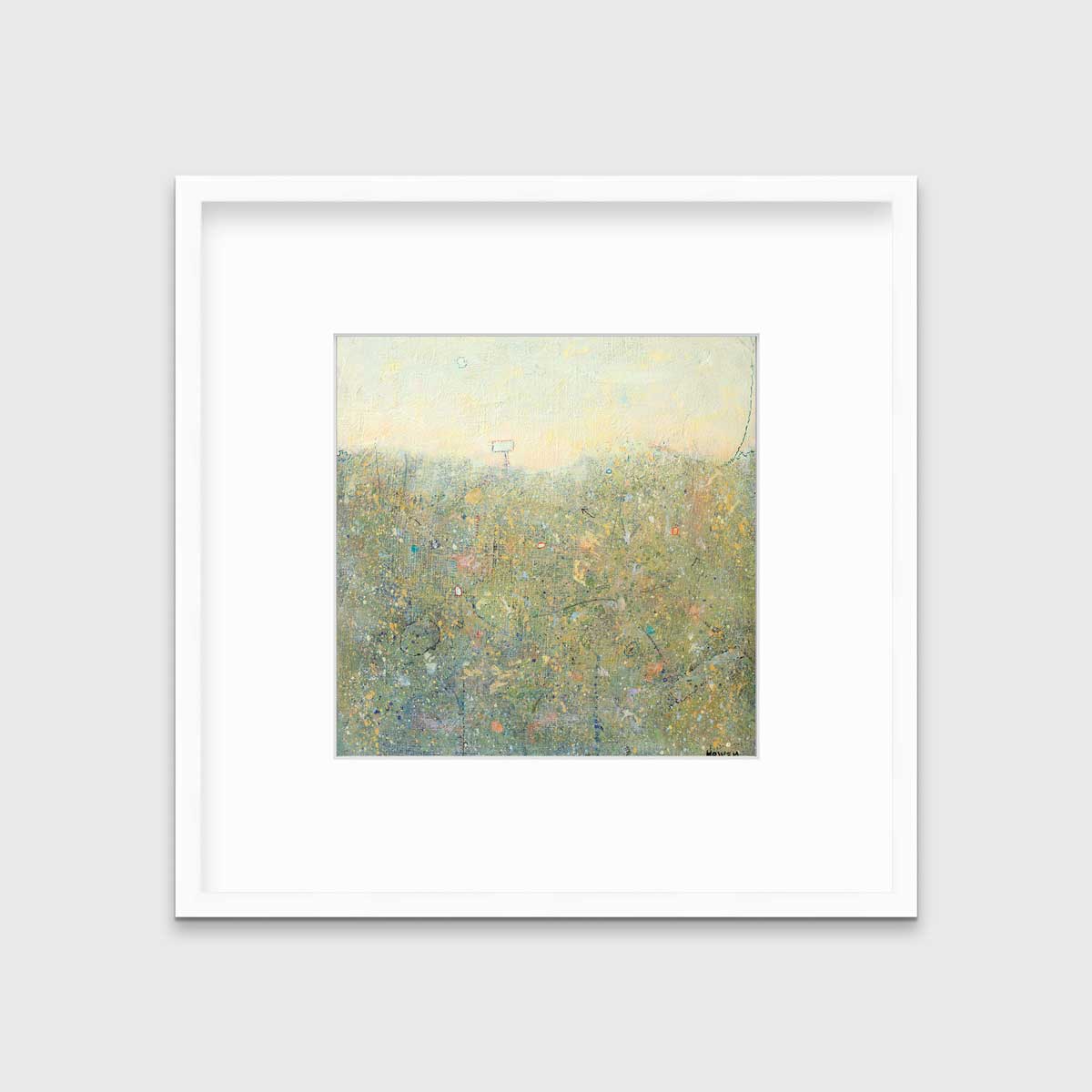 A yellow-green abstract landscape in a white frame with a mat hangs on a white wall.