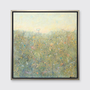 A yellow-green abstract landscape in a silver floater frame hangs on a white wall.