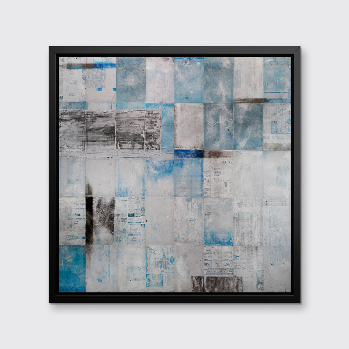A blue, grey and black abstract print in a black floater frame hangs on a white wall.