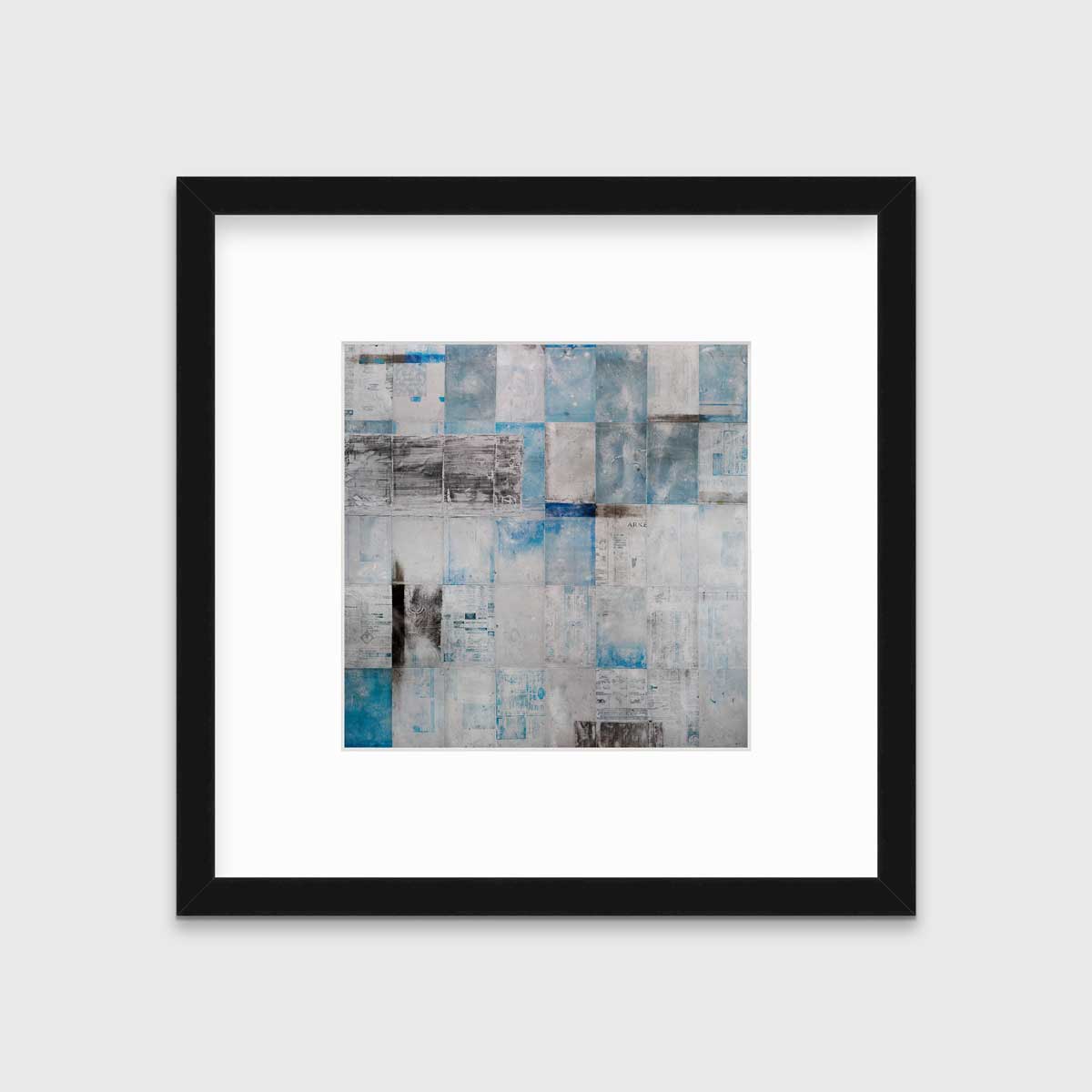 A blue, grey and black abstract print in a black frame with a mat hangs on a white wall.