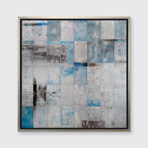 A blue, grey and black abstract print in a silver floater frame hangs on a white wall.